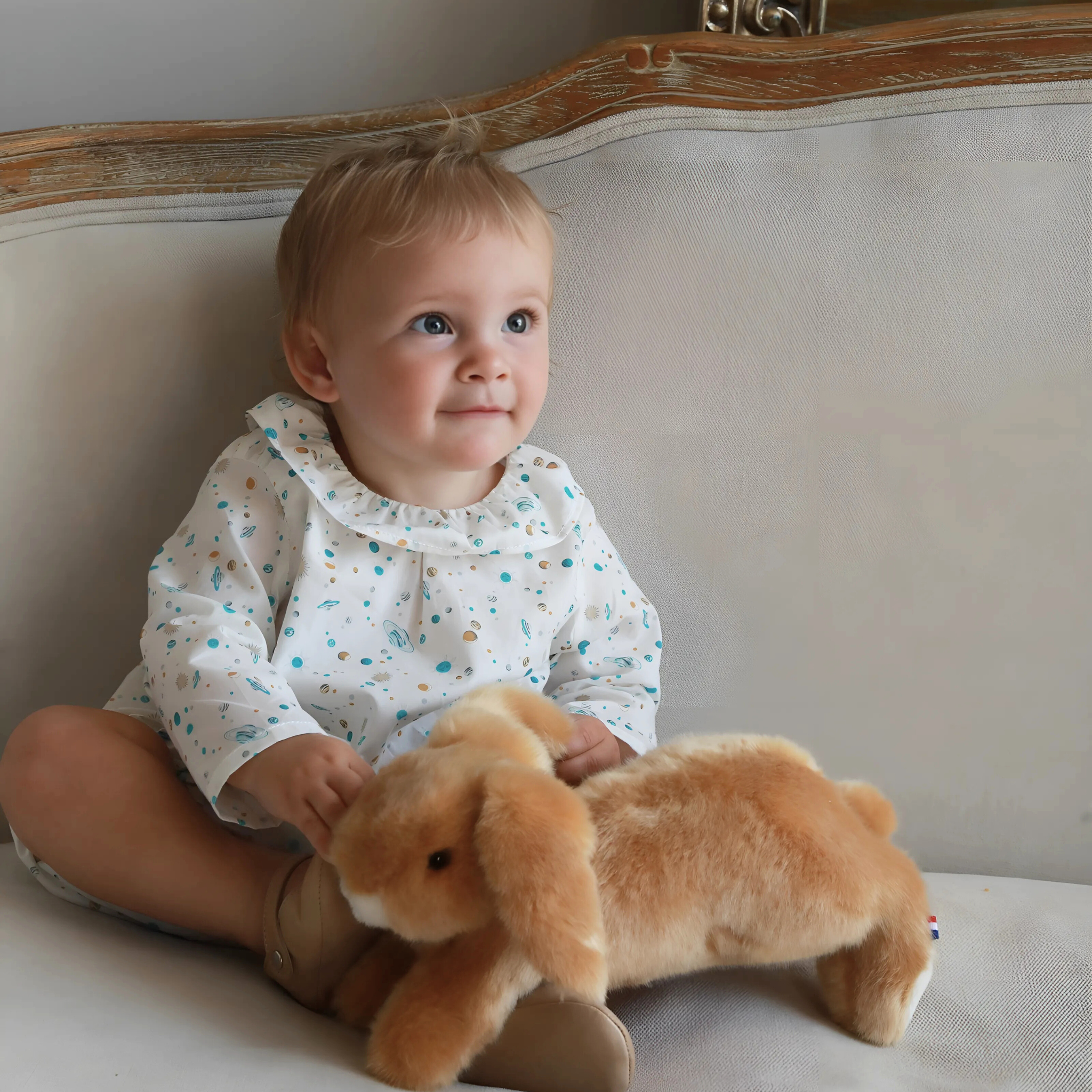 Child holding a plush toy on a light-colored couch