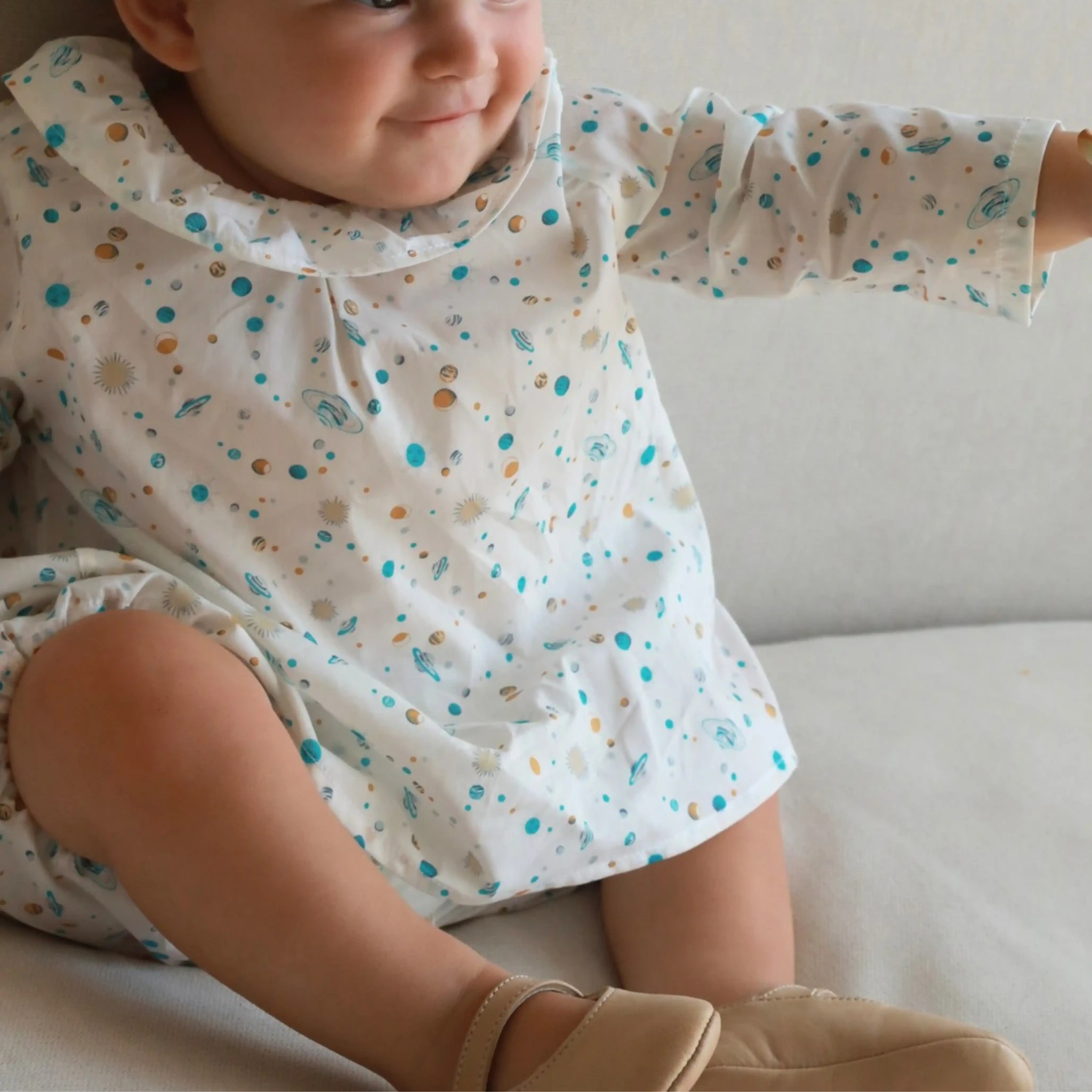 Child wearing a patterned blouse sitting on a couch